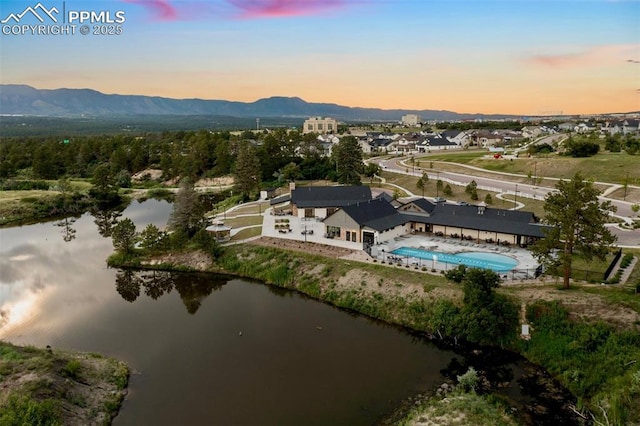 aerial view at dusk featuring a water and mountain view