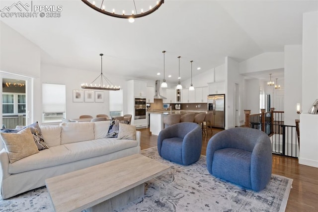 living room with sink, hardwood / wood-style floors, vaulted ceiling, and an inviting chandelier