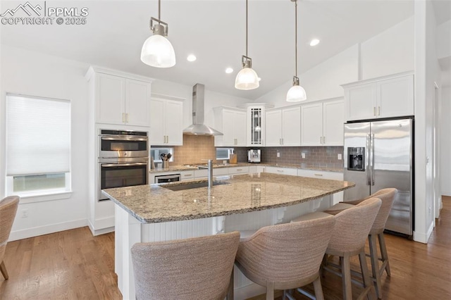 kitchen featuring white cabinetry, wall chimney range hood, and stainless steel appliances