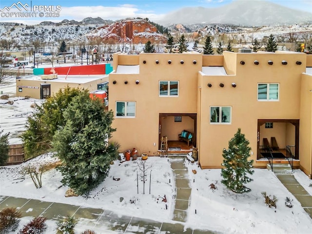 snow covered rear of property featuring a mountain view