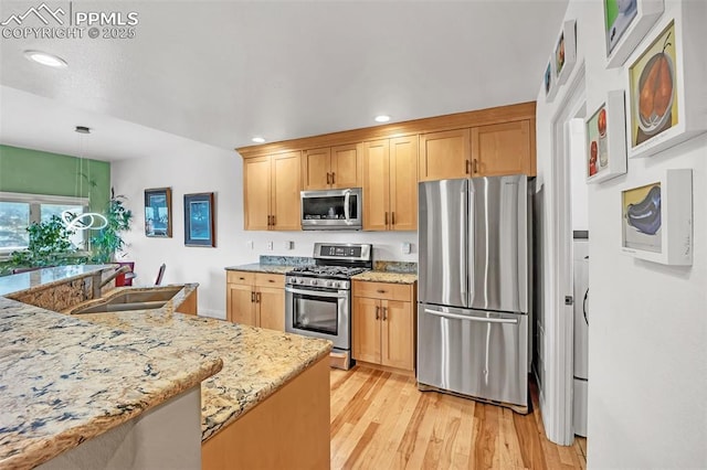 kitchen with sink, decorative light fixtures, light stone counters, light hardwood / wood-style floors, and stainless steel appliances