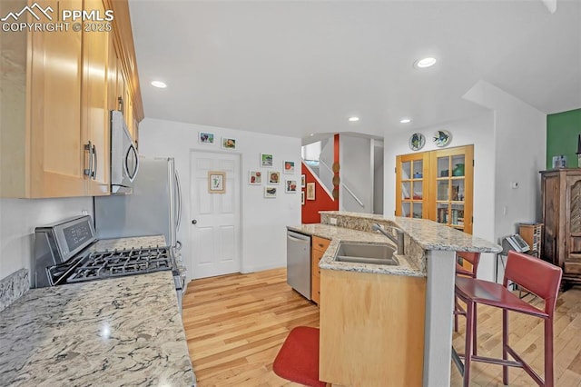 kitchen with sink, an island with sink, stainless steel appliances, light stone counters, and a breakfast bar area