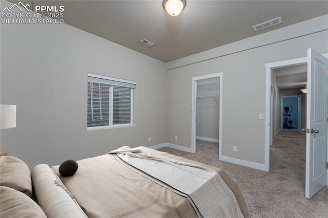 bedroom with light carpet, baseboards, a walk in closet, and a closet