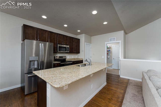 kitchen featuring stainless steel appliances, a sink, baseboards, an island with sink, and dark brown cabinetry