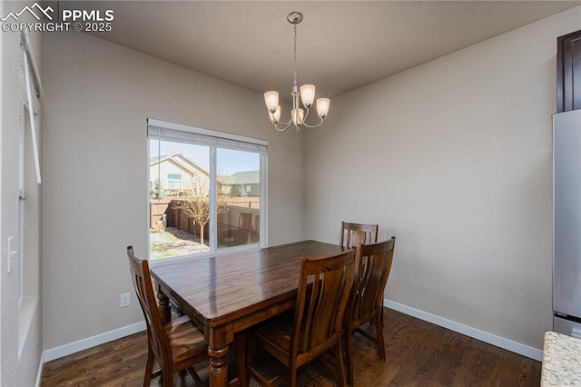 dining space with a chandelier, dark wood-style flooring, and baseboards