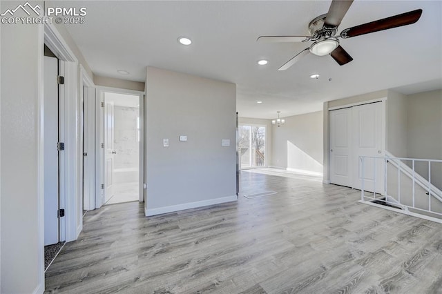 unfurnished room featuring light hardwood / wood-style floors and ceiling fan with notable chandelier