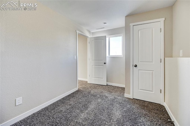 spare room featuring dark colored carpet