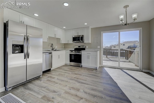 kitchen with stainless steel appliances, white cabinets, hanging light fixtures, light hardwood / wood-style flooring, and sink