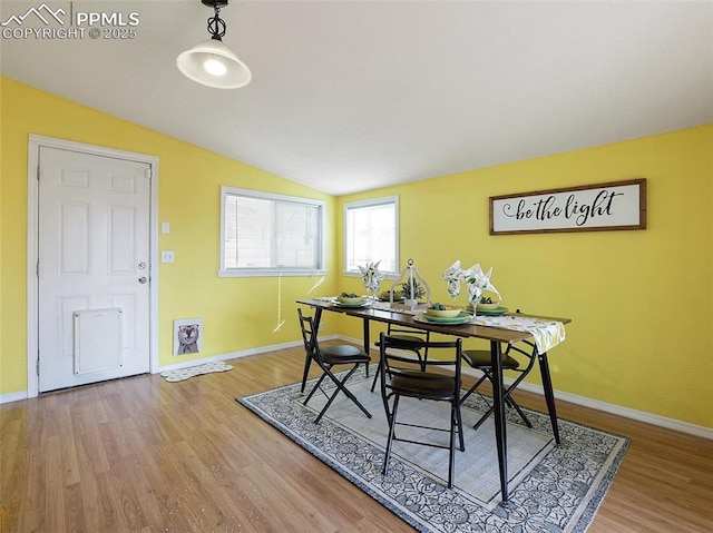 dining area featuring vaulted ceiling and wood-type flooring