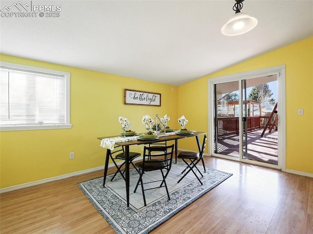 dining area featuring light wood-type flooring and vaulted ceiling