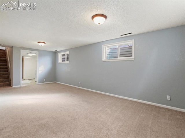 basement featuring light carpet and a textured ceiling