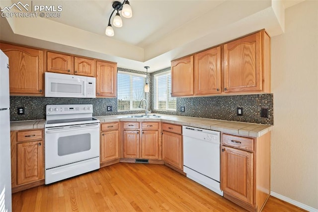 kitchen with light hardwood / wood-style floors, sink, white appliances, and tile countertops