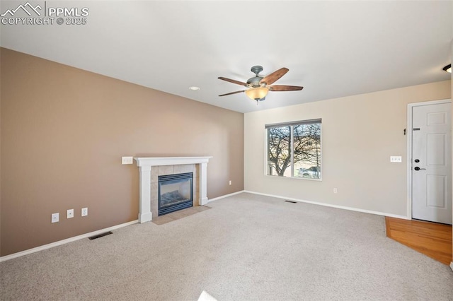 unfurnished living room featuring ceiling fan, light colored carpet, and a tile fireplace