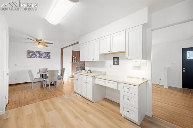 kitchen featuring ceiling fan, light stone countertops, white cabinets, and light wood-type flooring