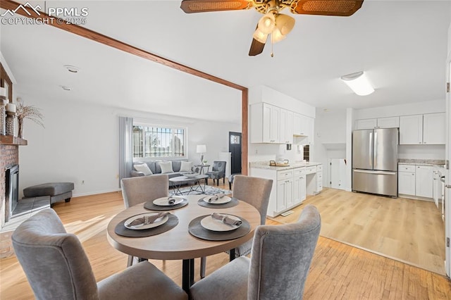 dining space featuring a brick fireplace, light hardwood / wood-style floors, and ceiling fan