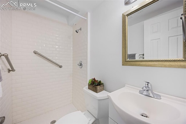 bathroom featuring toilet, a tile shower, and vanity