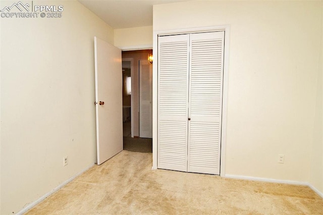 unfurnished bedroom with light carpet and a closet