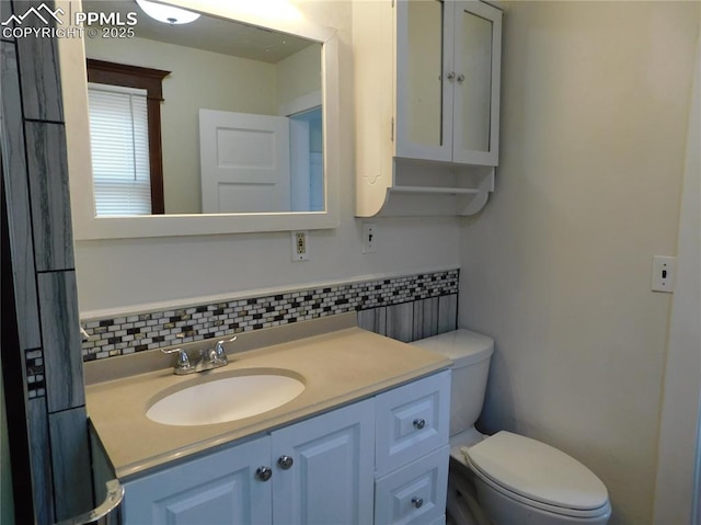 bathroom featuring toilet, vanity, and tasteful backsplash