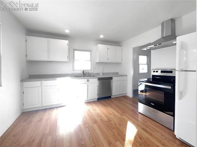 kitchen with white cabinetry, light hardwood / wood-style floors, stainless steel appliances, wall chimney exhaust hood, and sink