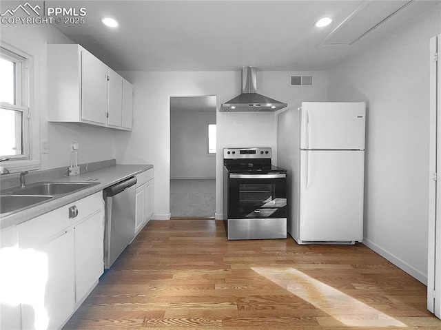 kitchen featuring white cabinetry, light hardwood / wood-style floors, appliances with stainless steel finishes, wall chimney exhaust hood, and sink