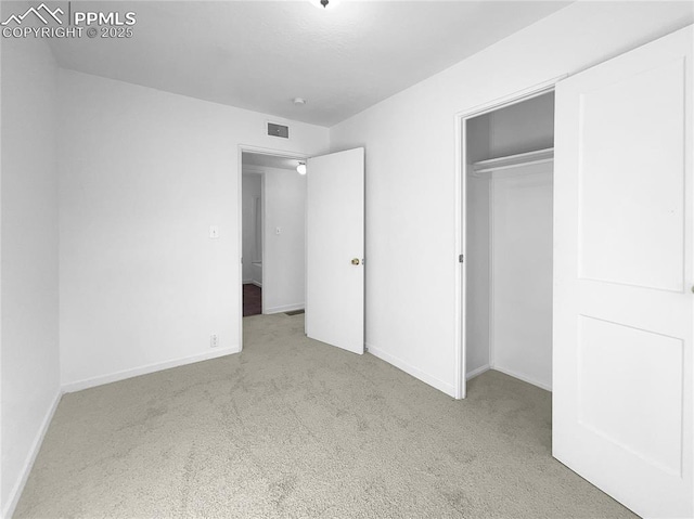 unfurnished bedroom featuring a closet and light carpet