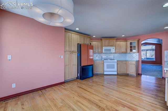 kitchen featuring light brown cabinetry, backsplash, white appliances, and light hardwood / wood-style flooring