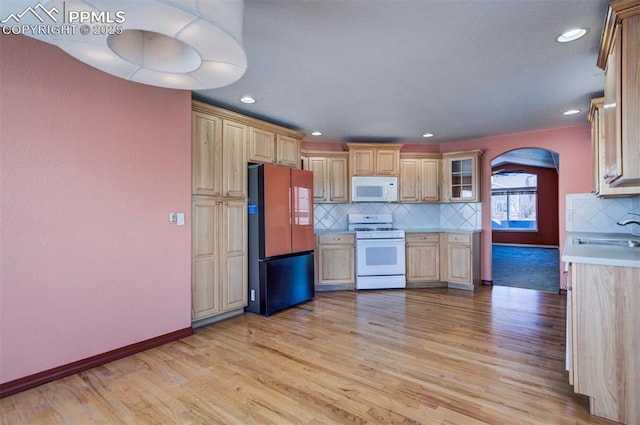 kitchen with light brown cabinetry, sink, white appliances, light hardwood / wood-style floors, and backsplash