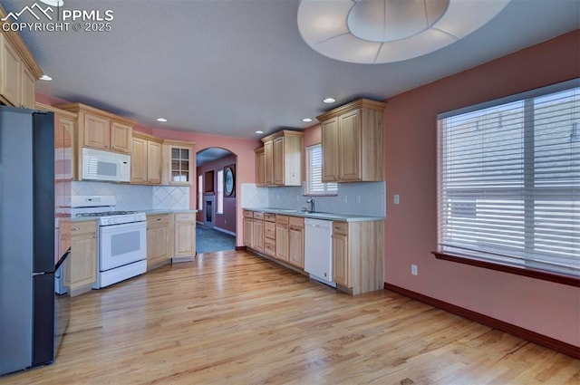 kitchen with white appliances, light brown cabinetry, light hardwood / wood-style flooring, and backsplash