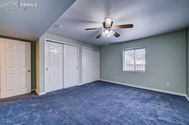 unfurnished bedroom featuring multiple closets, ceiling fan, a textured ceiling, and dark colored carpet