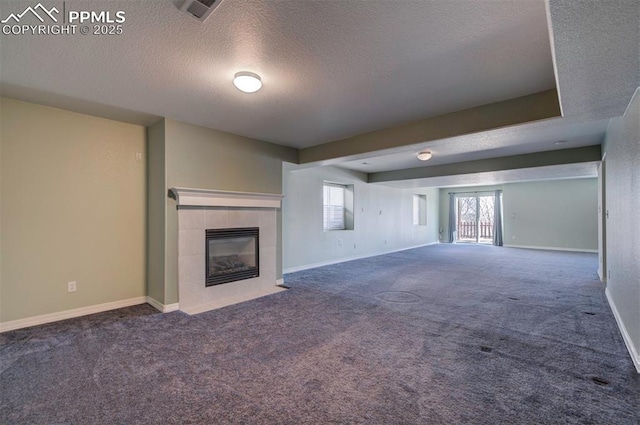 unfurnished living room with a tile fireplace, carpet flooring, and a textured ceiling