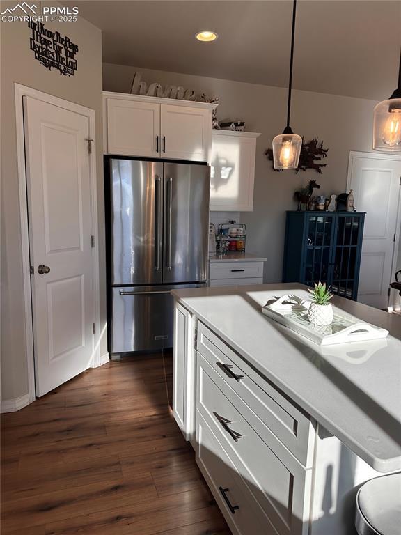 kitchen featuring white cabinets, hanging light fixtures, stainless steel fridge, and dark hardwood / wood-style flooring