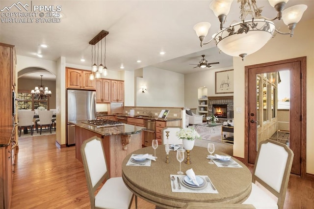 dining area featuring sink, ceiling fan with notable chandelier, and light hardwood / wood-style flooring