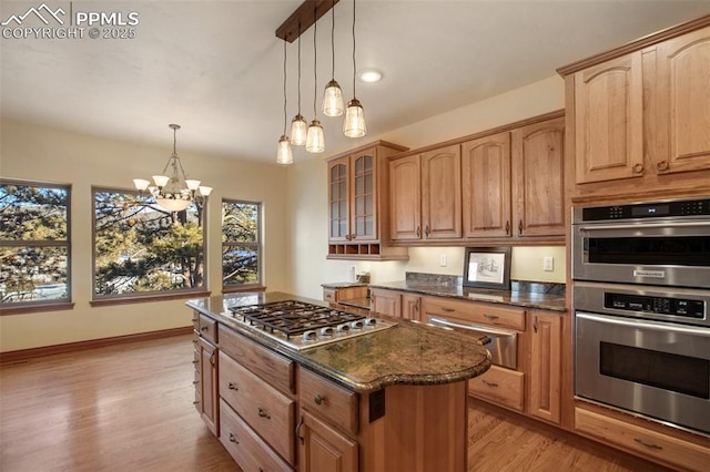 kitchen with hanging light fixtures, a wealth of natural light, dark stone counters, and appliances with stainless steel finishes