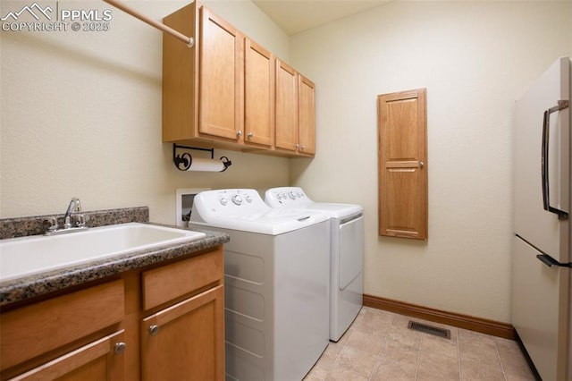 clothes washing area featuring independent washer and dryer, cabinets, and sink