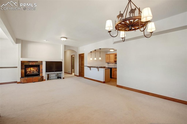 unfurnished living room with a fireplace, light carpet, and a notable chandelier