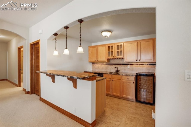 kitchen with pendant lighting, backsplash, a kitchen breakfast bar, kitchen peninsula, and beverage cooler