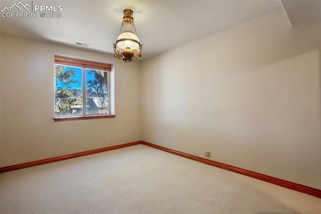 spare room with carpet floors and a notable chandelier