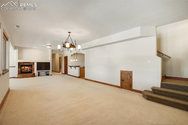 unfurnished living room featuring carpet flooring, an inviting chandelier, and a fireplace