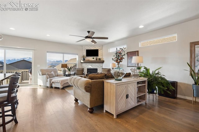 living room featuring dark wood-type flooring, ceiling fan, and a brick fireplace