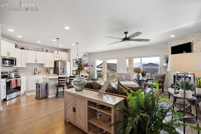 living room featuring ceiling fan, sink, a fireplace, and light hardwood / wood-style floors