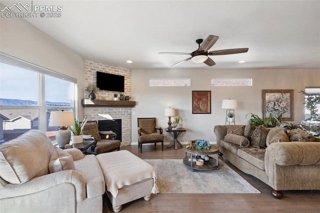 living room featuring hardwood / wood-style flooring, ceiling fan, and a brick fireplace