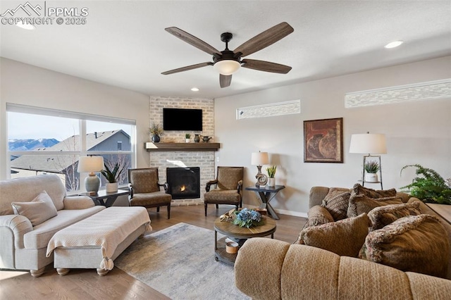 living room with a mountain view, a fireplace, hardwood / wood-style floors, and ceiling fan