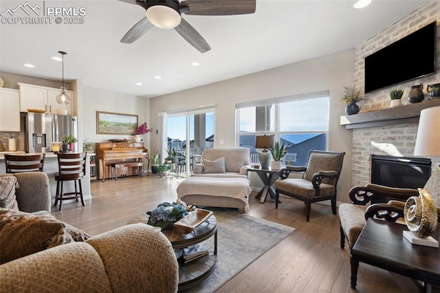 living room with a fireplace, light hardwood / wood-style floors, and ceiling fan