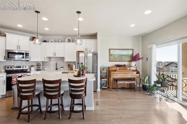 kitchen featuring a kitchen island, pendant lighting, white cabinetry, sink, and stainless steel appliances