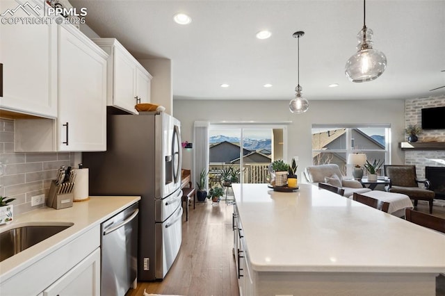 kitchen featuring white cabinetry, a healthy amount of sunlight, stainless steel dishwasher, and decorative light fixtures