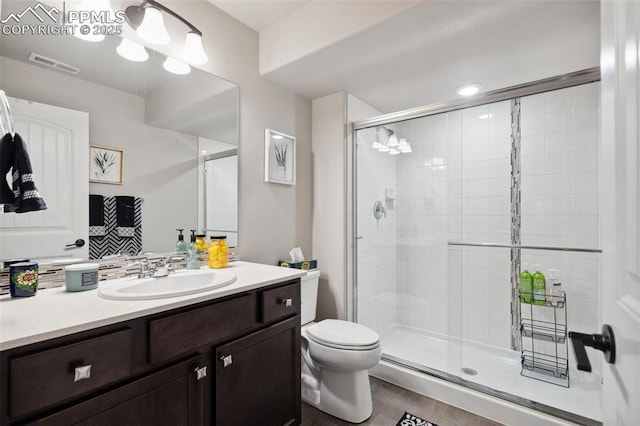 bathroom featuring vanity, toilet, backsplash, and walk in shower