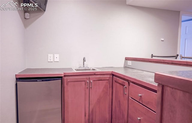 kitchen featuring dishwashing machine, sink, and stainless steel fridge