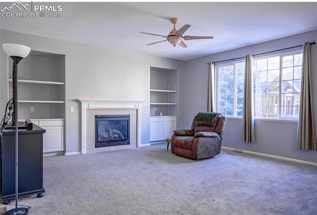 living room with built in features, a tile fireplace, ceiling fan, and carpet