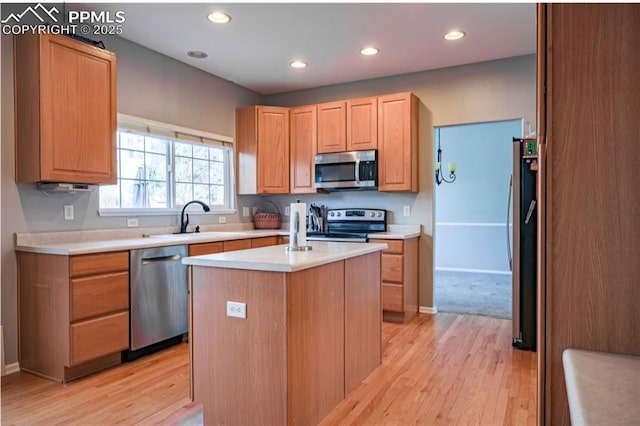 kitchen featuring appliances with stainless steel finishes, sink, a center island with sink, and light hardwood / wood-style flooring