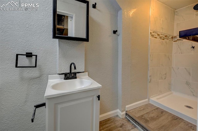 bathroom featuring hardwood / wood-style flooring, vanity, and a tile shower